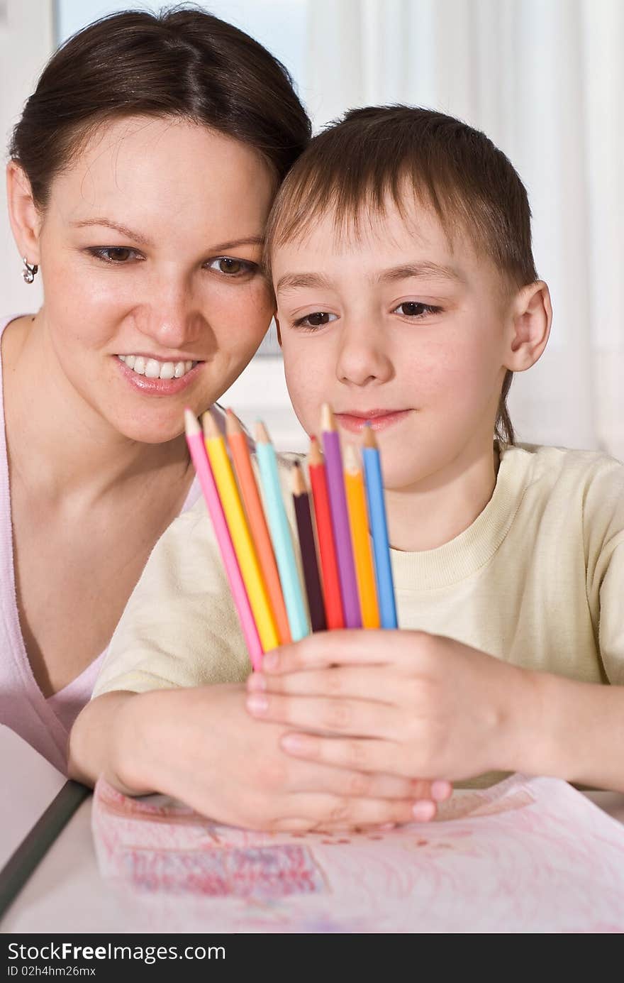Young mother sits with her son and look at pencils. Young mother sits with her son and look at pencils