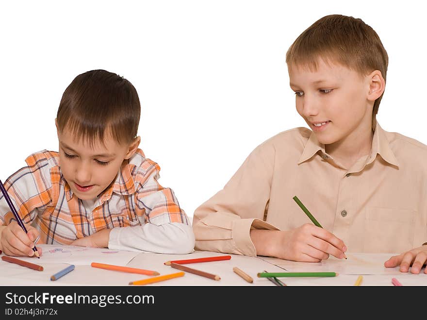 Two brothers sit at the table and draw