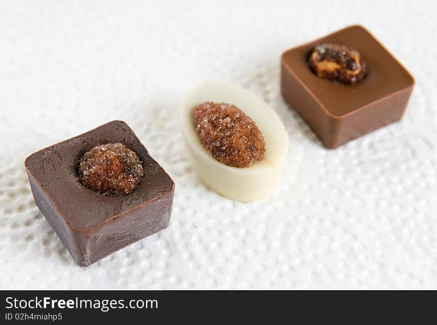 Chocolate candies with nuts on white surface. Chocolate candies with nuts on white surface