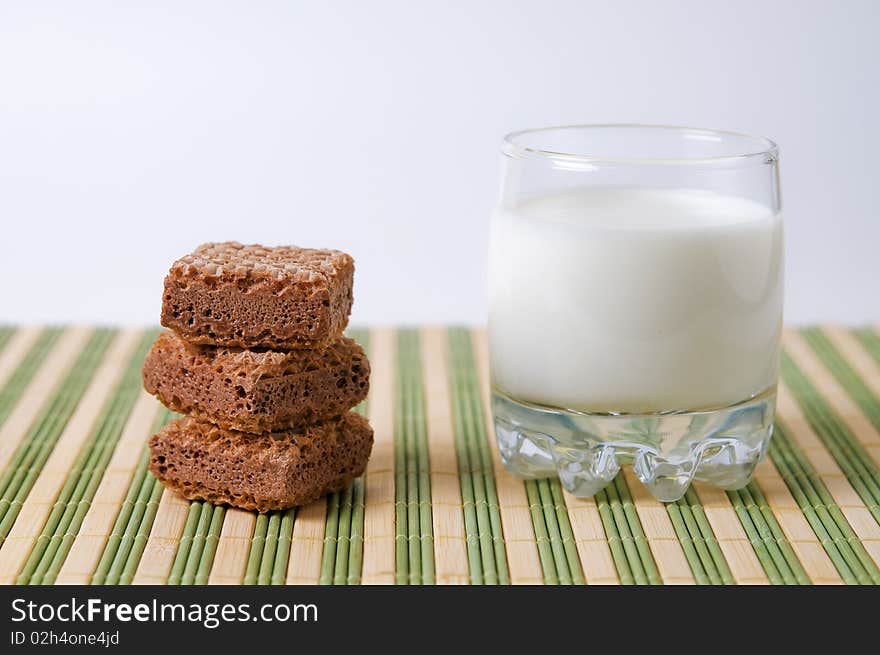 Glass with milk and waffles on stripe surface