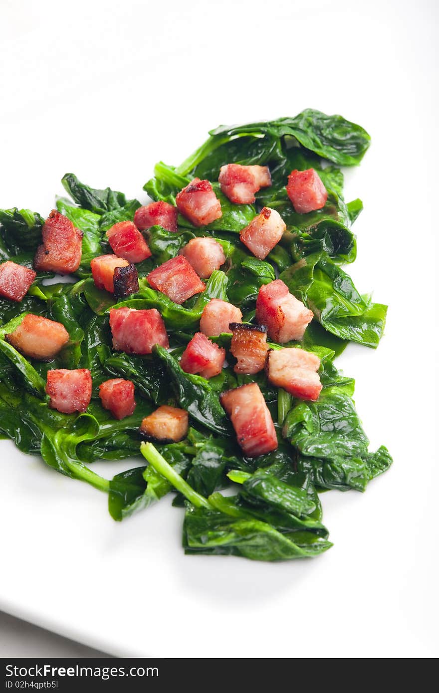 Fried spinach with bacon on plate