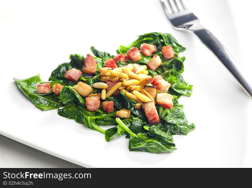 Fried spinach with bacon and pine nuts