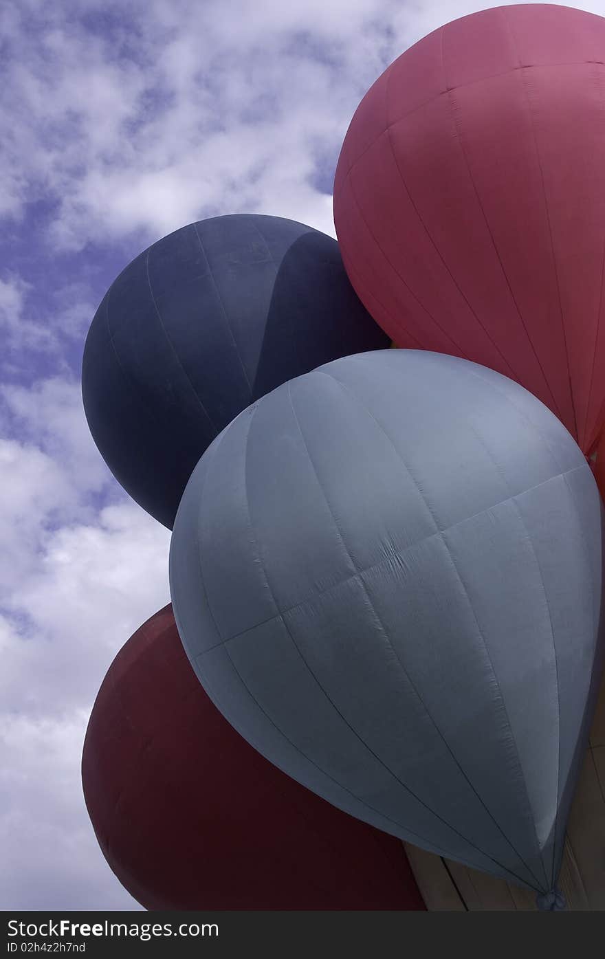 Red and blue hot air balloons attached together to one bucket before taking off