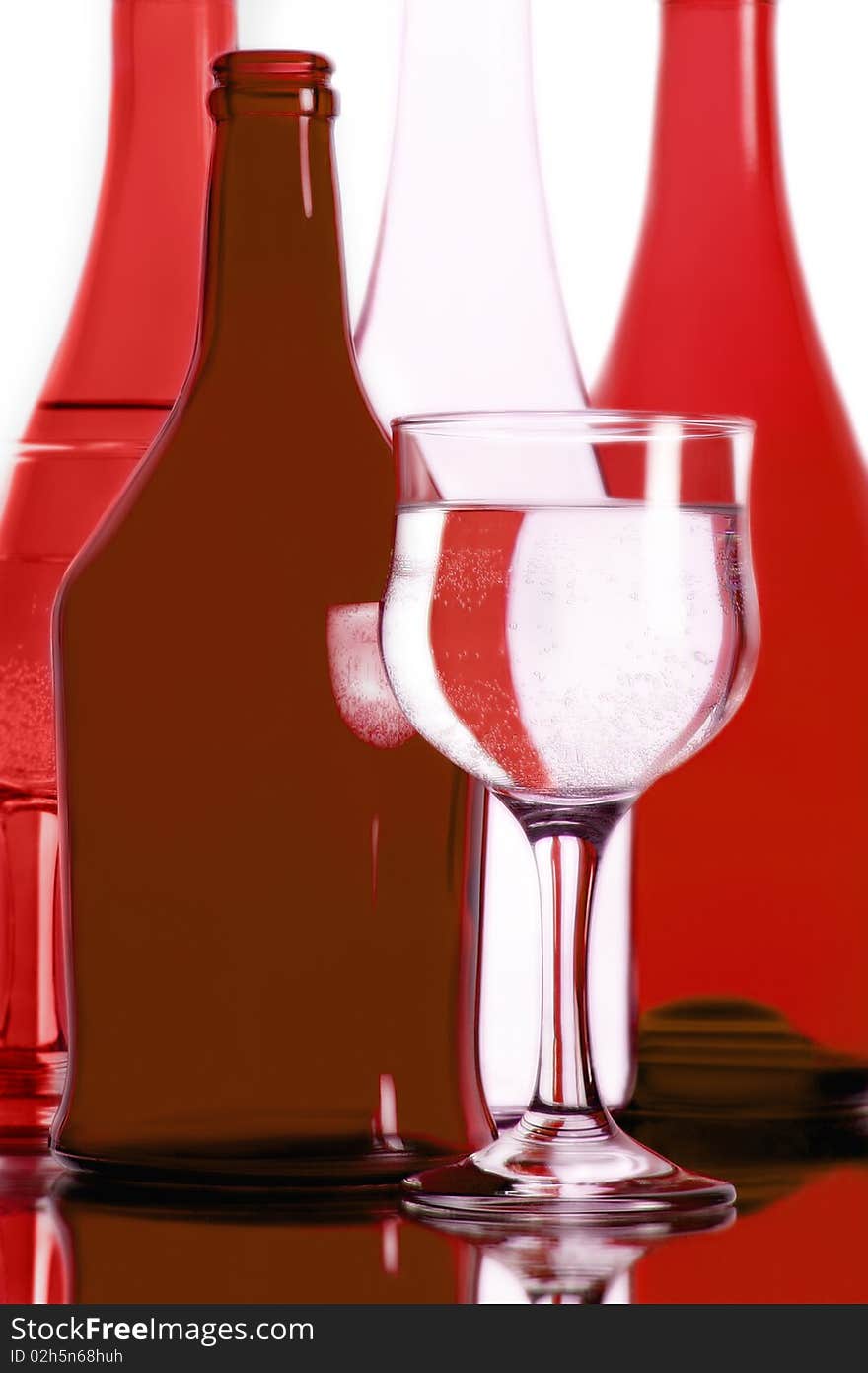 Still-life with red bottles and wineglass with a sparkling beverage. Still-life with red bottles and wineglass with a sparkling beverage.