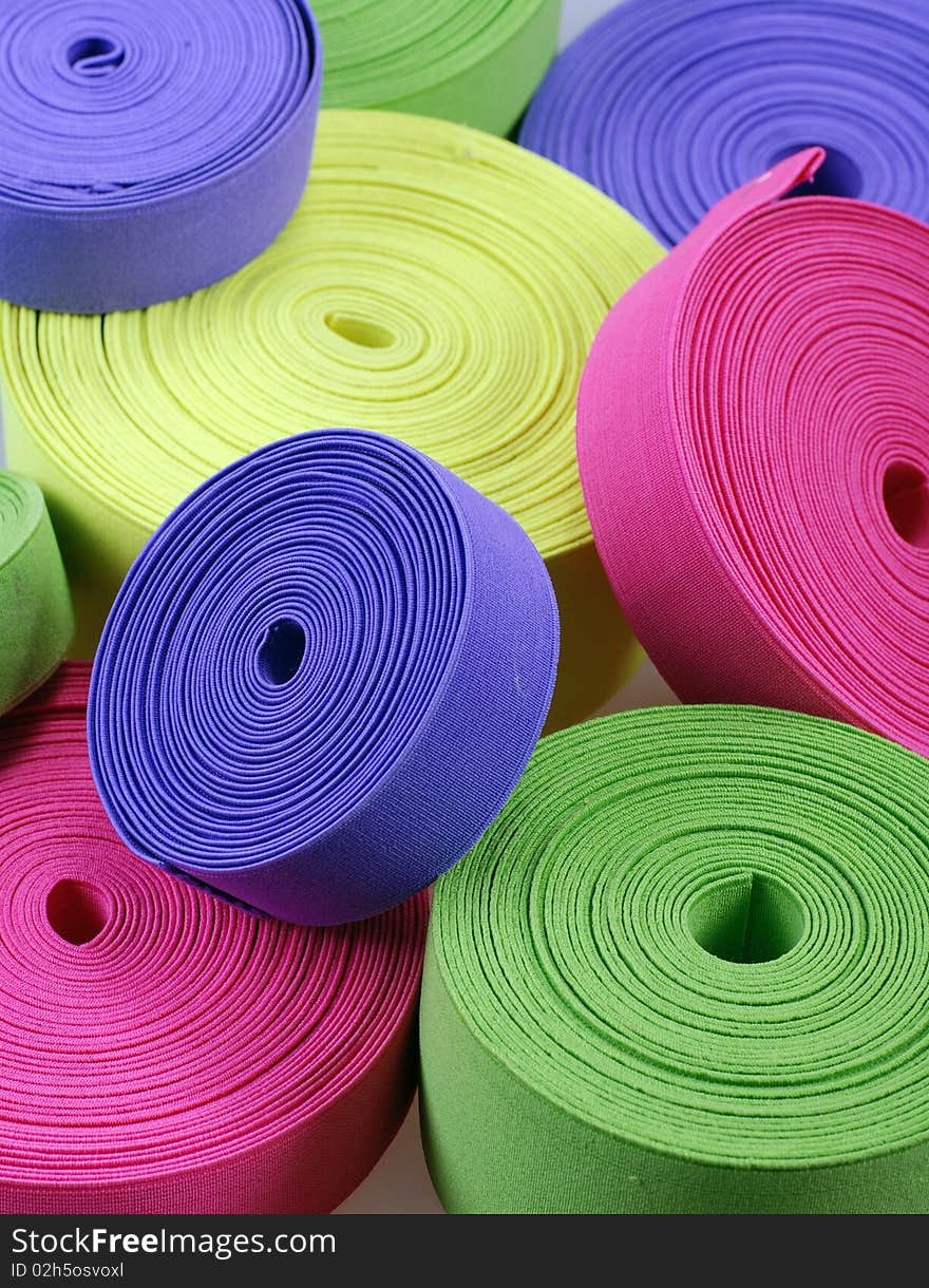 Group of multicolor elastic's bobbins. Bright vertical background with yellow,green, pink and purple spools. Group of multicolor elastic's bobbins. Bright vertical background with yellow,green, pink and purple spools.