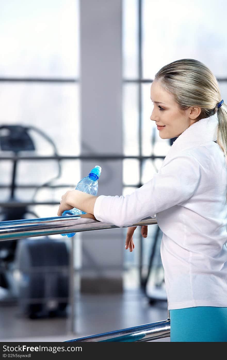 The young attractive girl in sports hall with a water bottle. The young attractive girl in sports hall with a water bottle