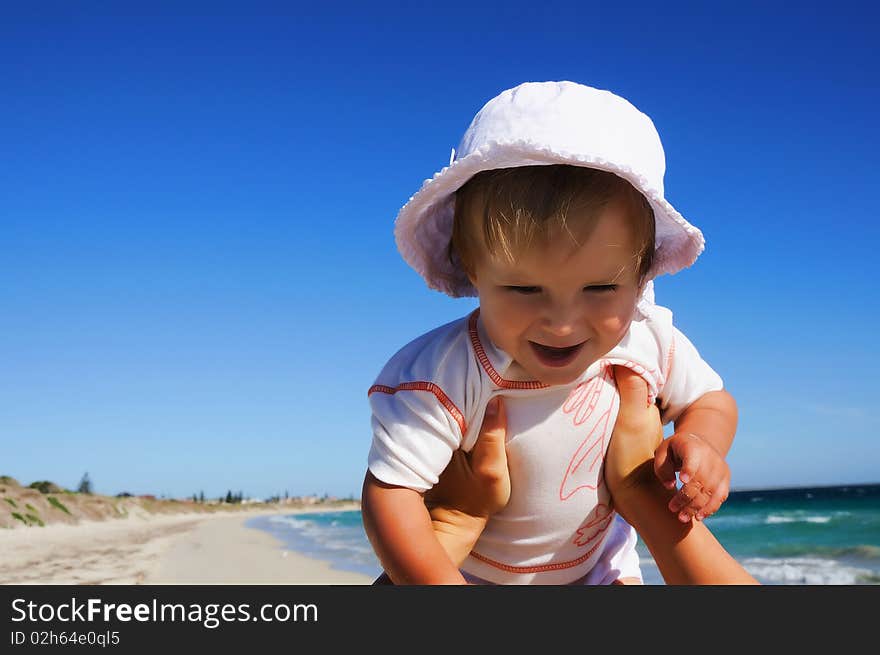 Charming little happy girl laughing in the arms of his mother, against the blue sky