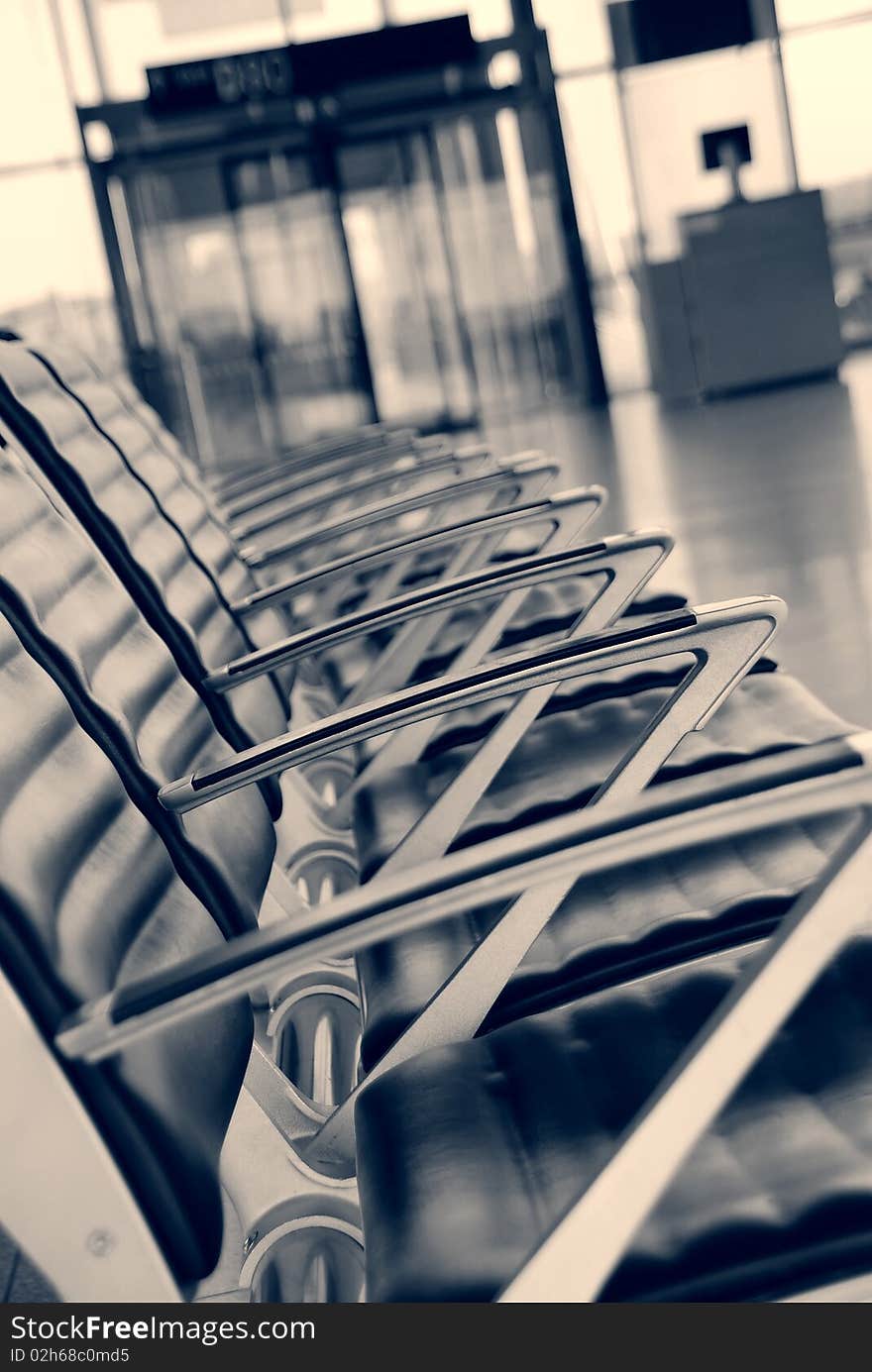 Empty chairs at the airport, entrance in the background. Empty chairs at the airport, entrance in the background