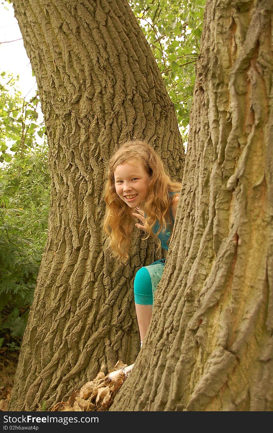 Portrait of young girl with red hair playing around trees