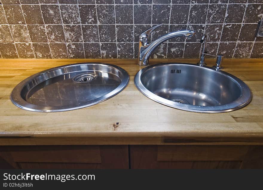 Double stainless steel kitchen sink on hard wood worktop. Double stainless steel kitchen sink on hard wood worktop