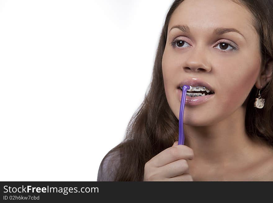 Girl with round toothbrush cleaning brackets with mouth open and eyes lifted up isolated over white background. Girl with round toothbrush cleaning brackets with mouth open and eyes lifted up isolated over white background