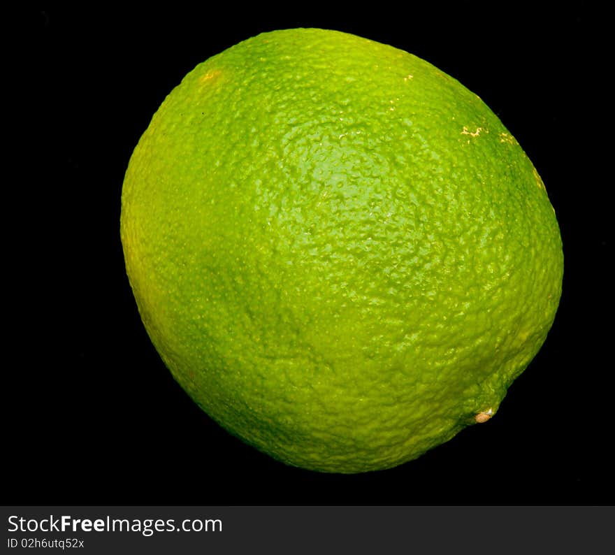 A macro image of a single lime isolated on a dark background. A macro image of a single lime isolated on a dark background.