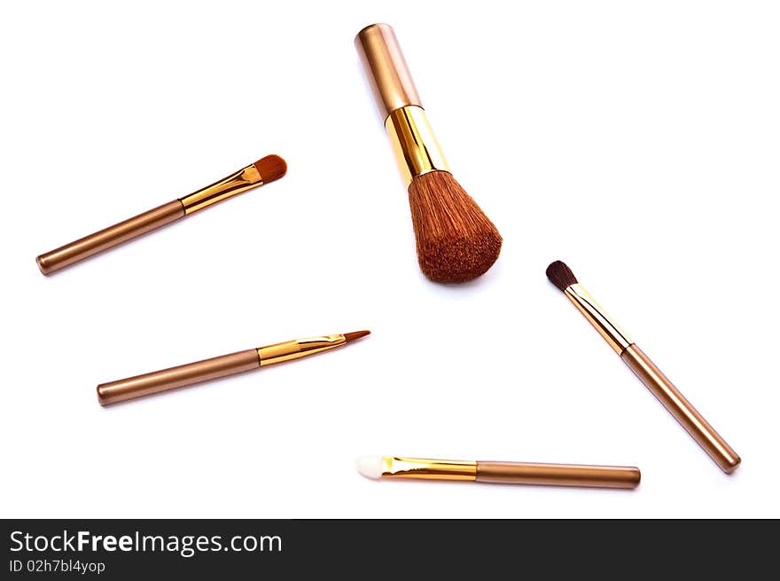 Gold metal makeup brushes isolated on white