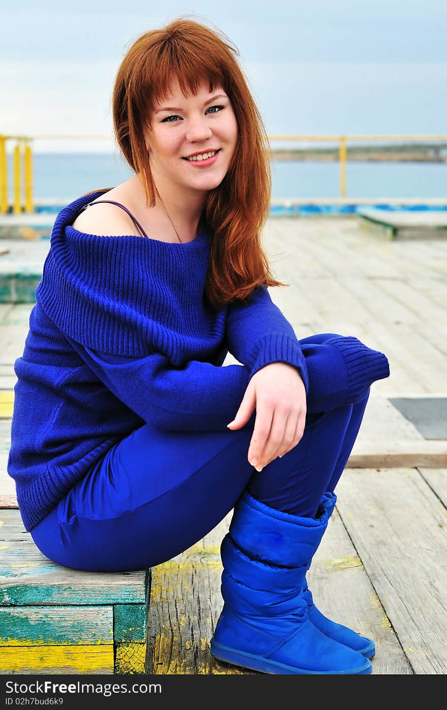 Young redheaded girl on a pier near the sea