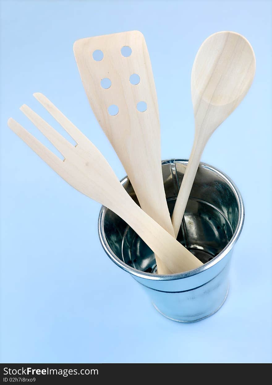 Wooden kitchen utensils isolated against a blue background