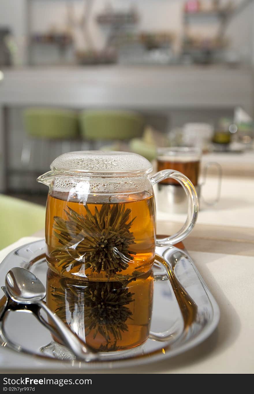 Glass tea pot with fresh green tea standing on an iron tray