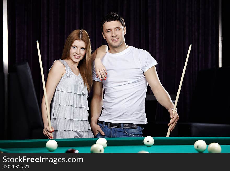 The young attractive couple plays billiards