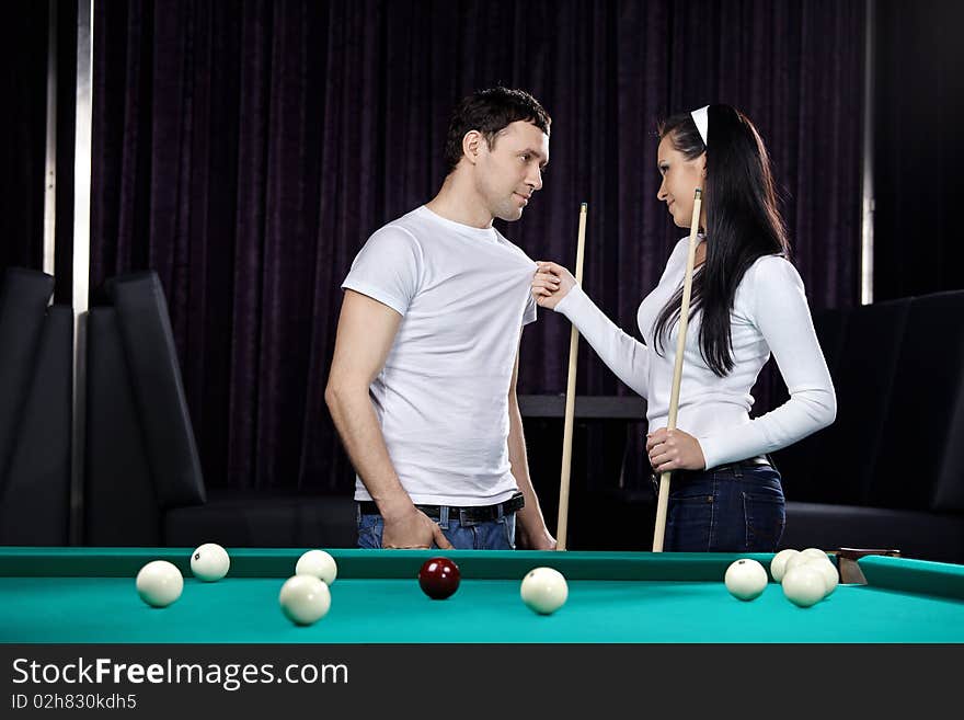 Young attractive couple near to a billiard table. Young attractive couple near to a billiard table