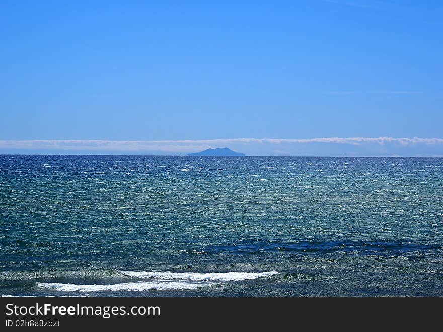 Giglio Island looks like a mirage on the horizon, in the Tyrrhenian Sea. Giglio Island looks like a mirage on the horizon, in the Tyrrhenian Sea.