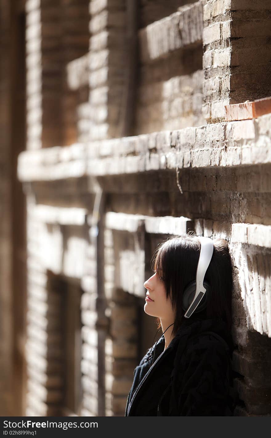 Young pierced girl listening music on urban background.