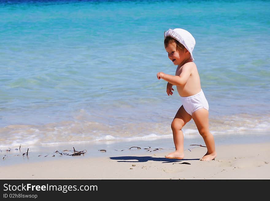 Small happy little girl running around on the beach