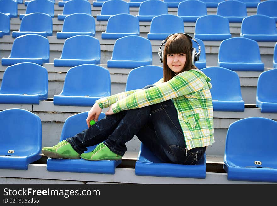 Girl at the stadium listening music. Girl at the stadium listening music