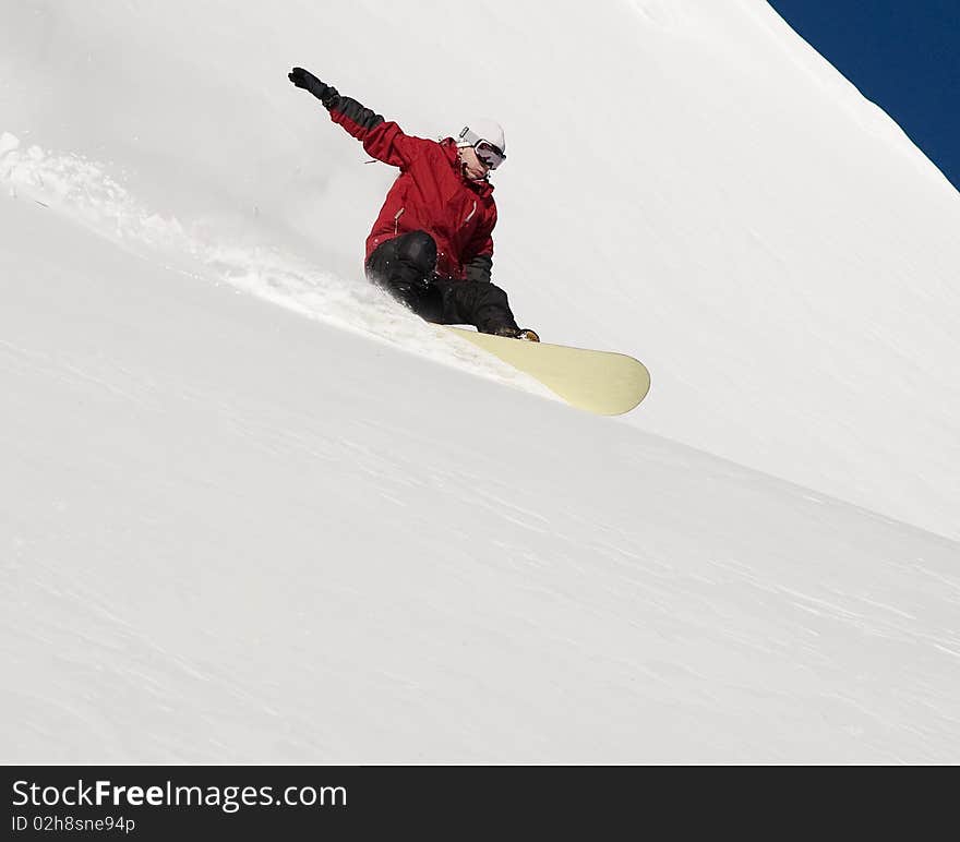 Snowboarder doing a toe side carve with deep blue sky in background