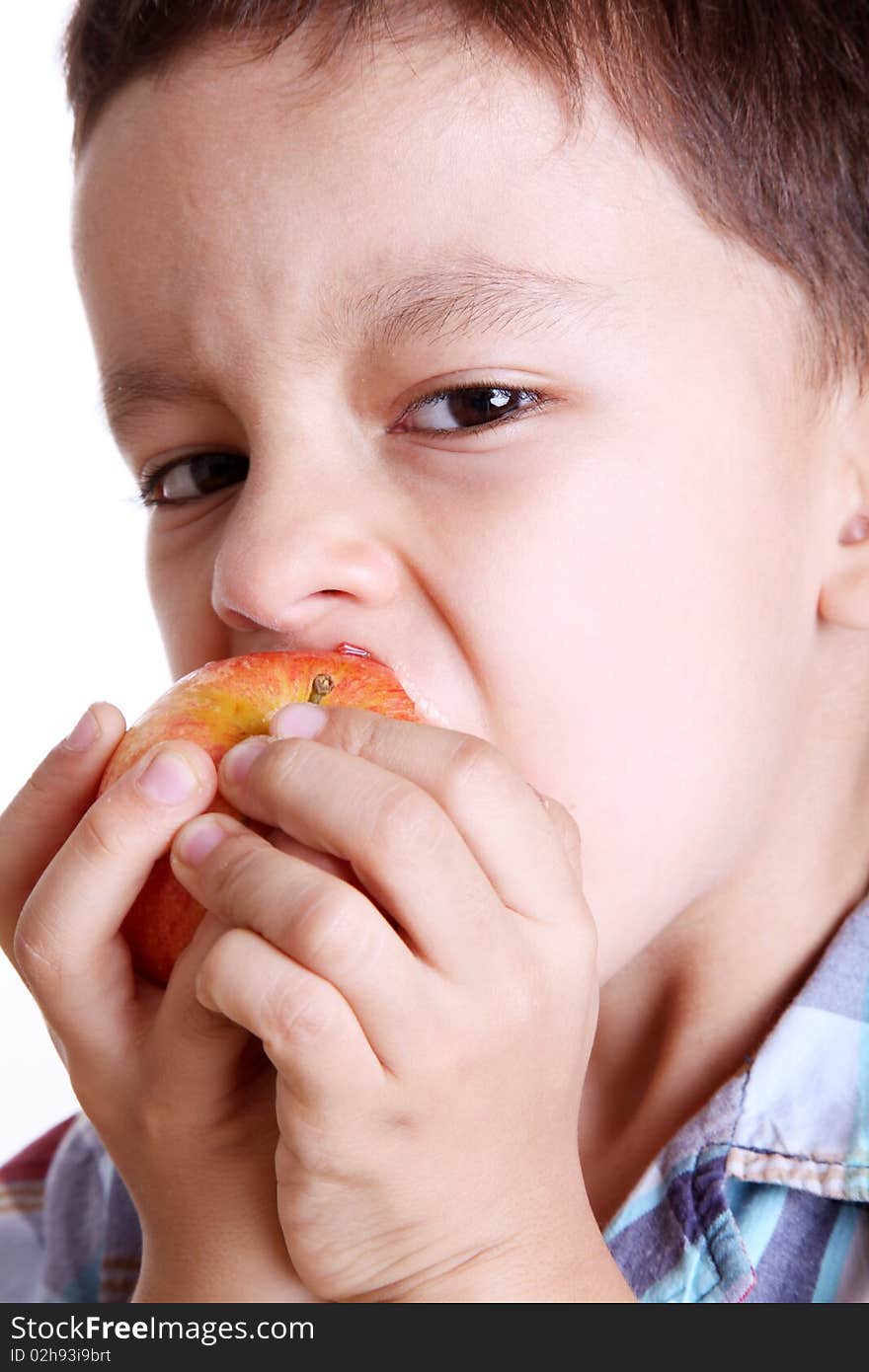 Child eating apple looking at camera over white background. Child eating apple looking at camera over white background