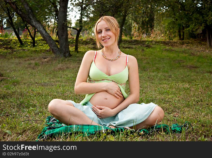 Pregnant woman on a grass and smiling