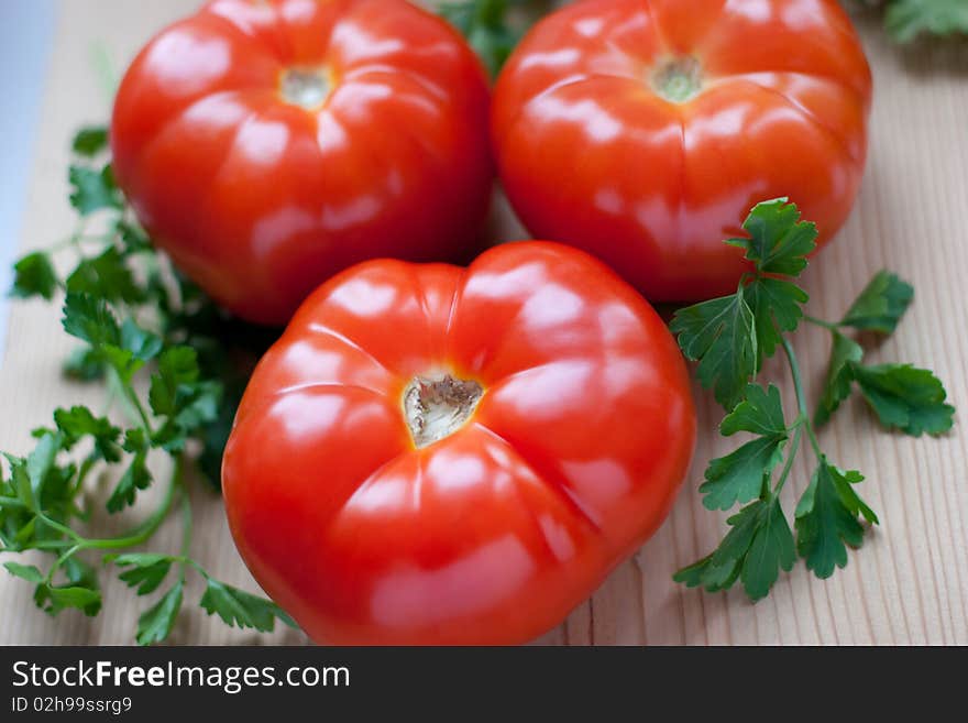 Three red tomatoes and parsley. Three red tomatoes and parsley