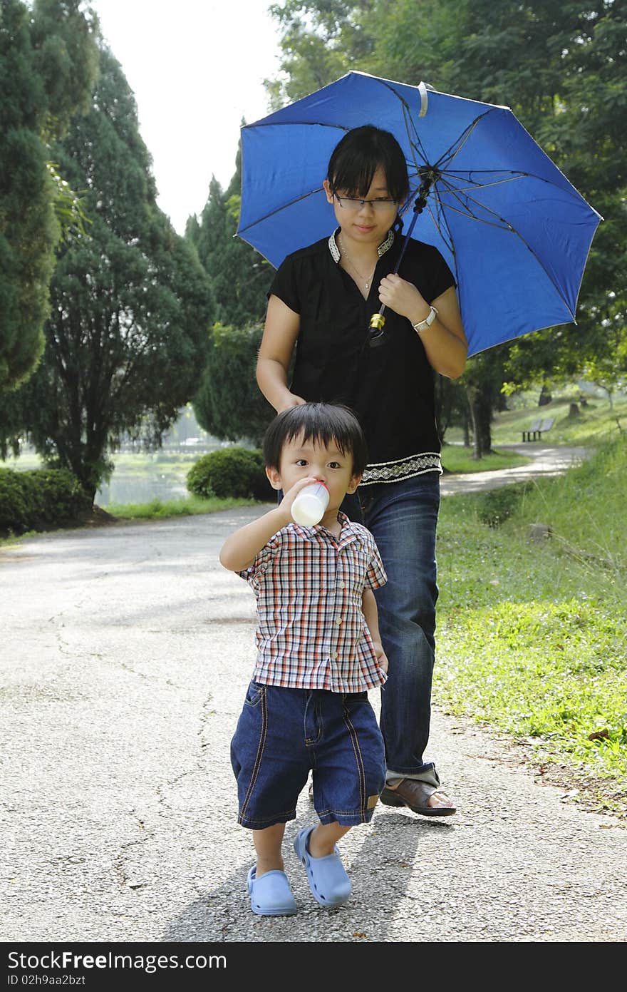 An Asian mother and her son walking in a public park. An Asian mother and her son walking in a public park