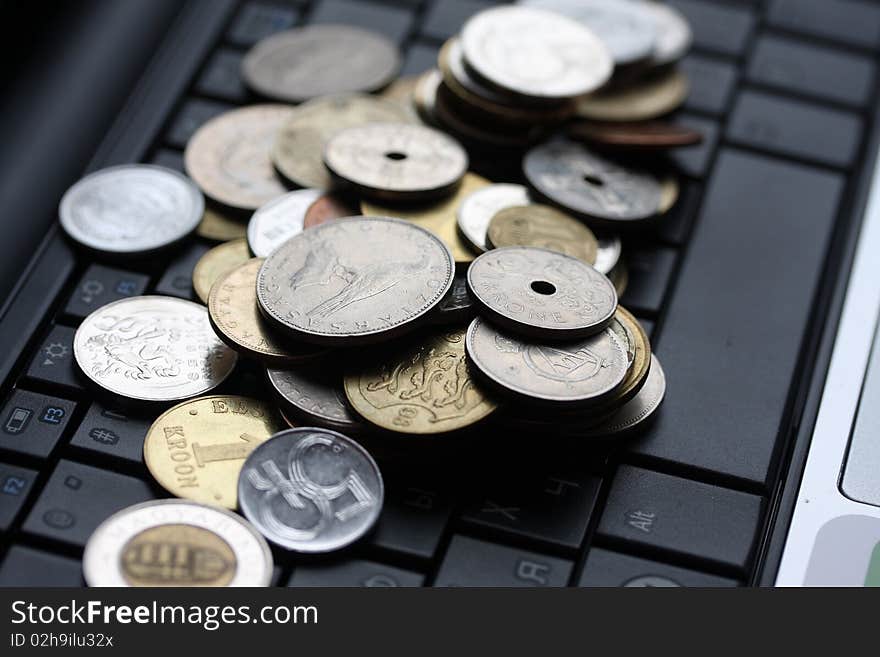 A shot of a laptop and world coins in an office environment, can be used as e-commerce concept