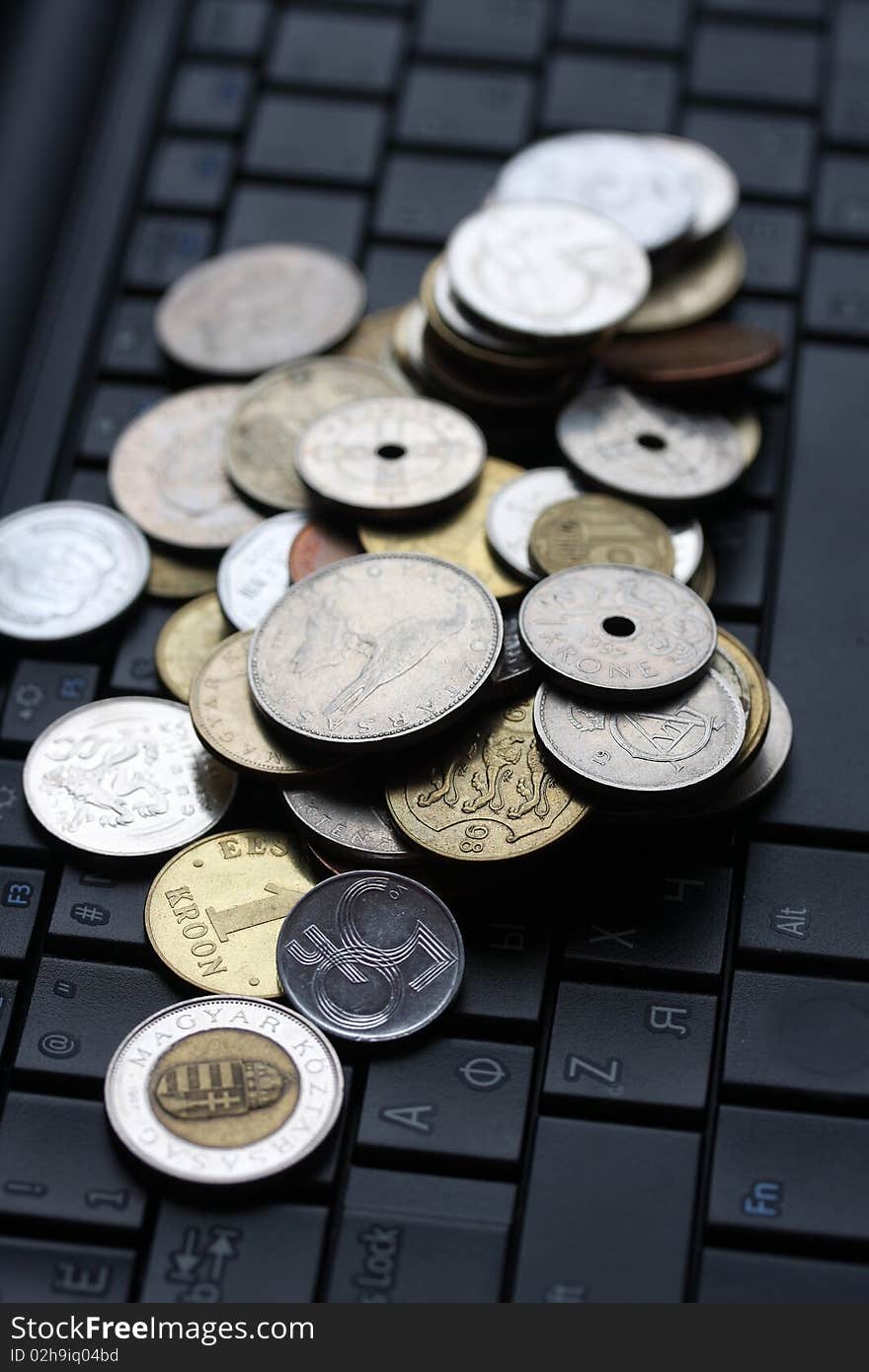 A shot of a laptop and world coins in an office environment, can be used as e-commerce concept