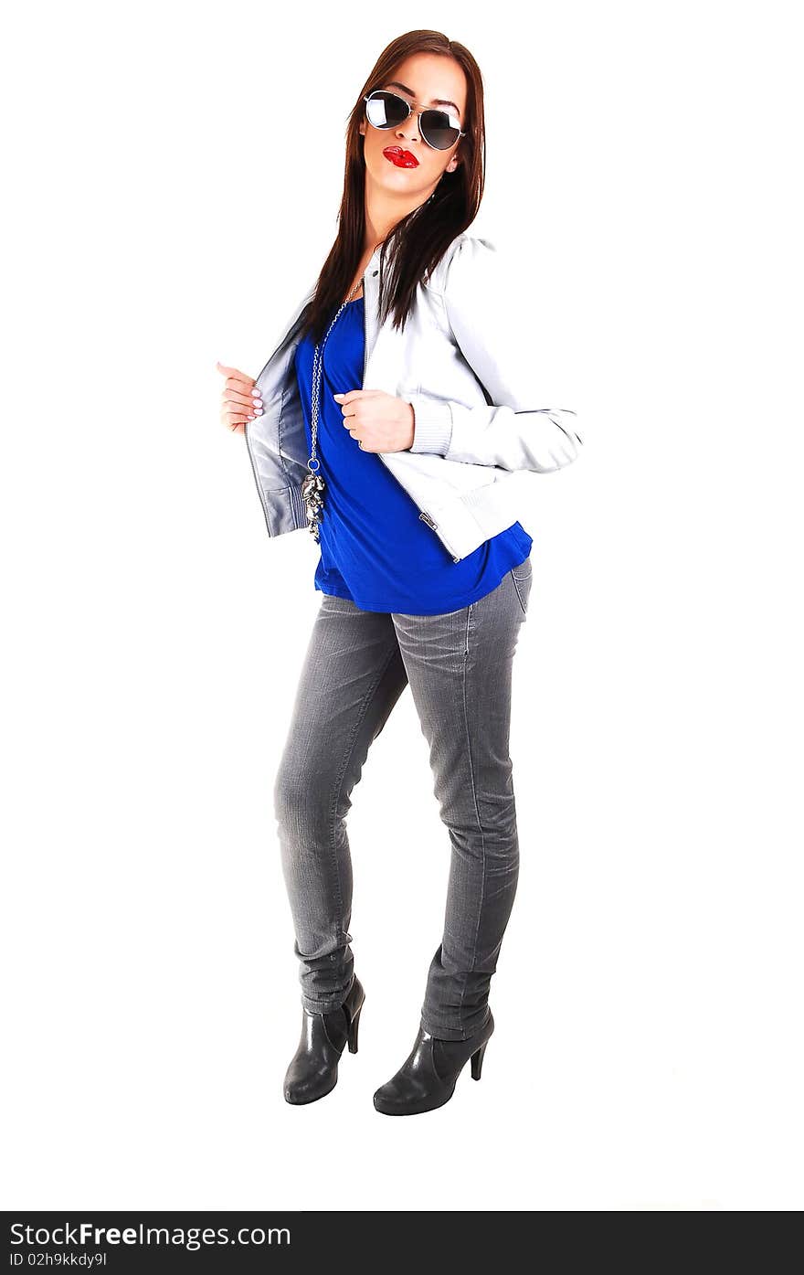 A young smiling woman in a blue sweater and light gray leather jacket pulling down her sunglasses, standing for white background. A young smiling woman in a blue sweater and light gray leather jacket pulling down her sunglasses, standing for white background.