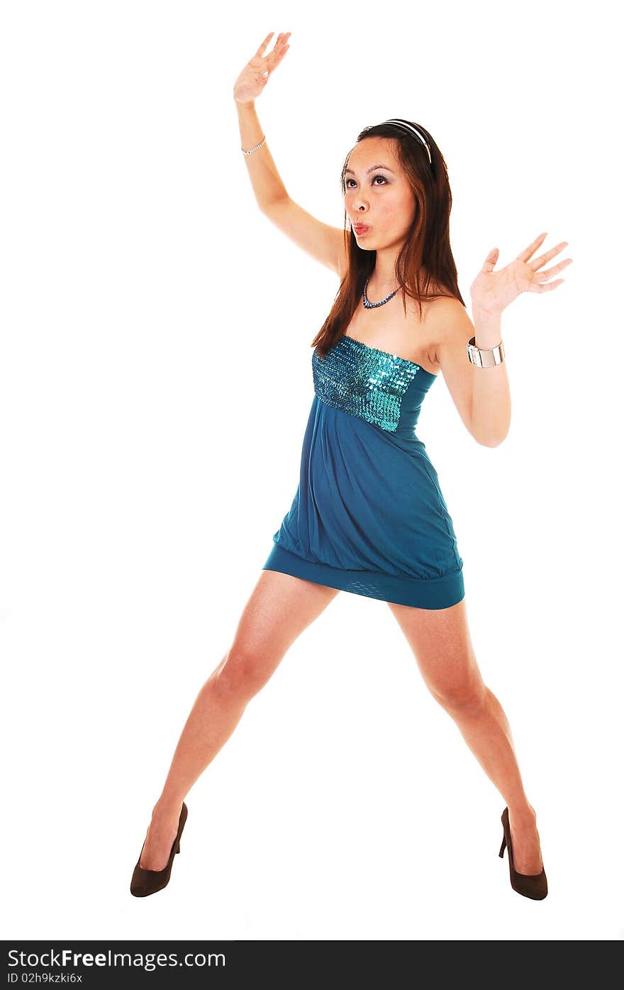 A young Asian woman standing in a studio in an short turquoise dress and high heels, her arms up in the air, for white background. A young Asian woman standing in a studio in an short turquoise dress and high heels, her arms up in the air, for white background.