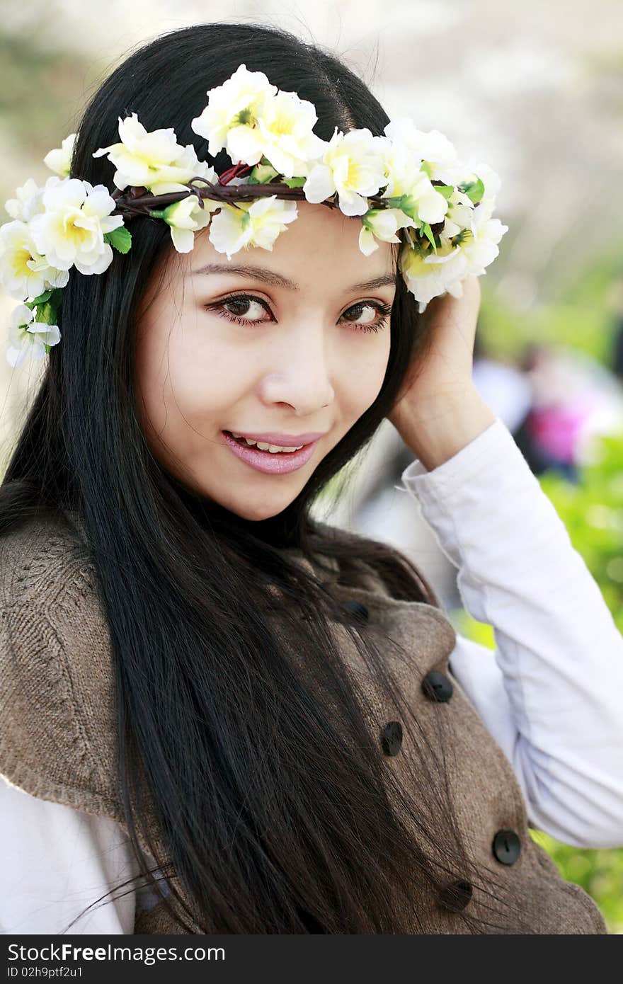 Spring portrait of young smiling girl with garlands outdoors.