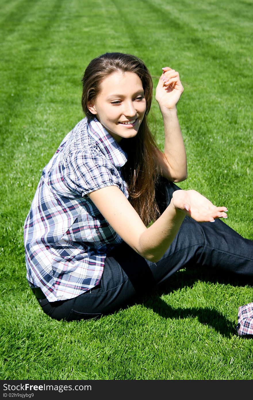 Happy girl sitting on the green grass