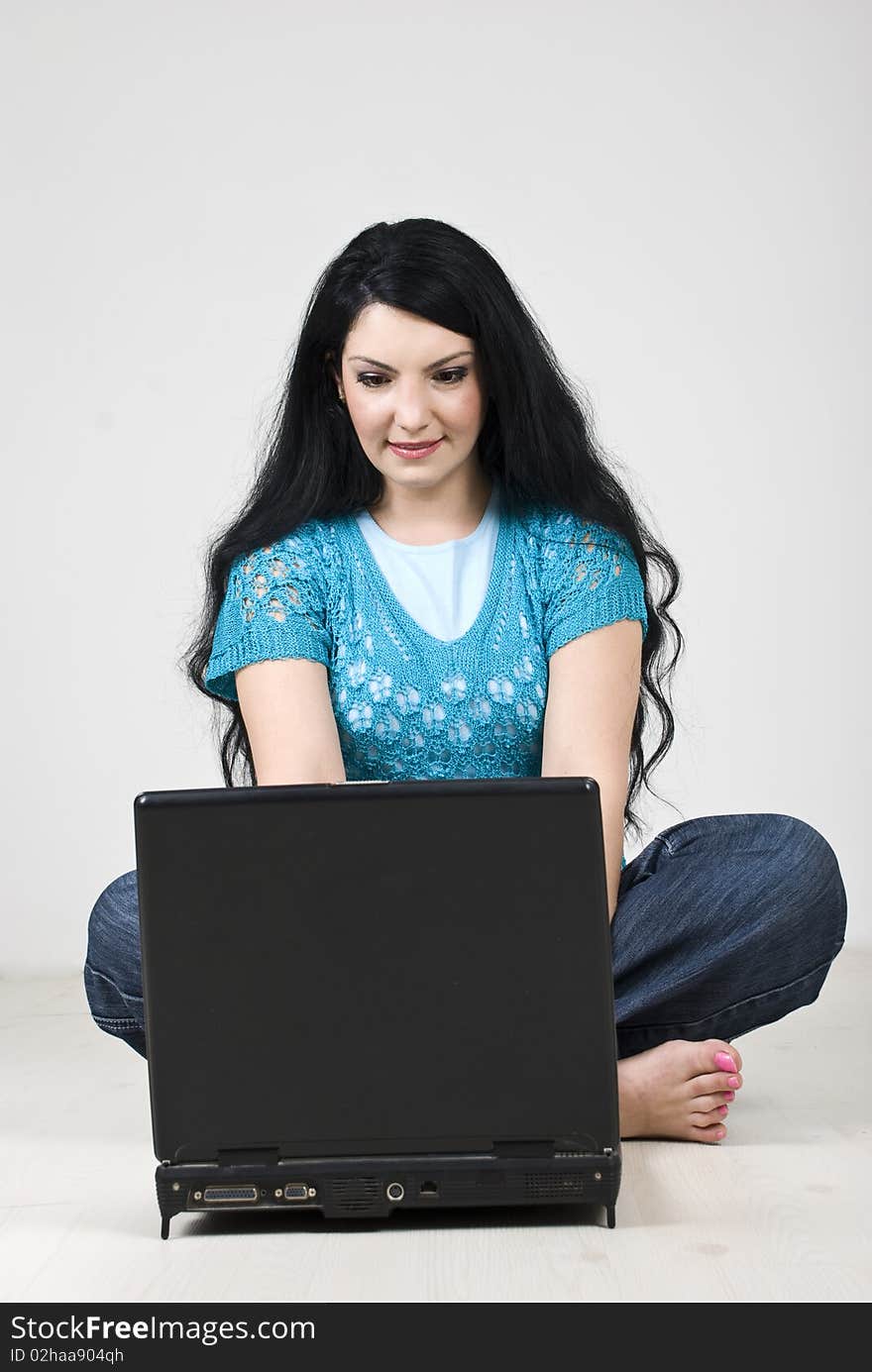 Young woman sitting with legs crossed on floor and working on laptop,see more in People on couch or wooden floor. Young woman sitting with legs crossed on floor and working on laptop,see more in People on couch or wooden floor