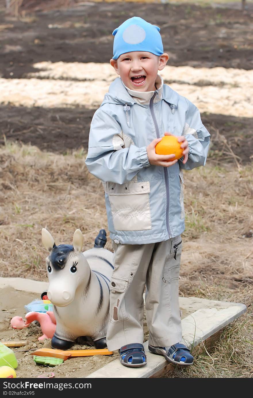 The boy plays in the street with toys and has control over an orange. The boy plays in the street with toys and has control over an orange