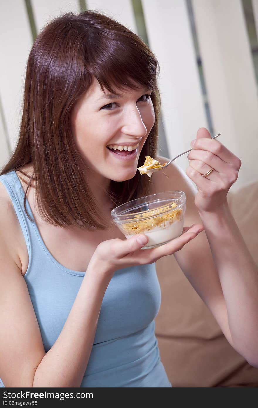 Happy young woman eating tasty corn flakes. Happy young woman eating tasty corn flakes