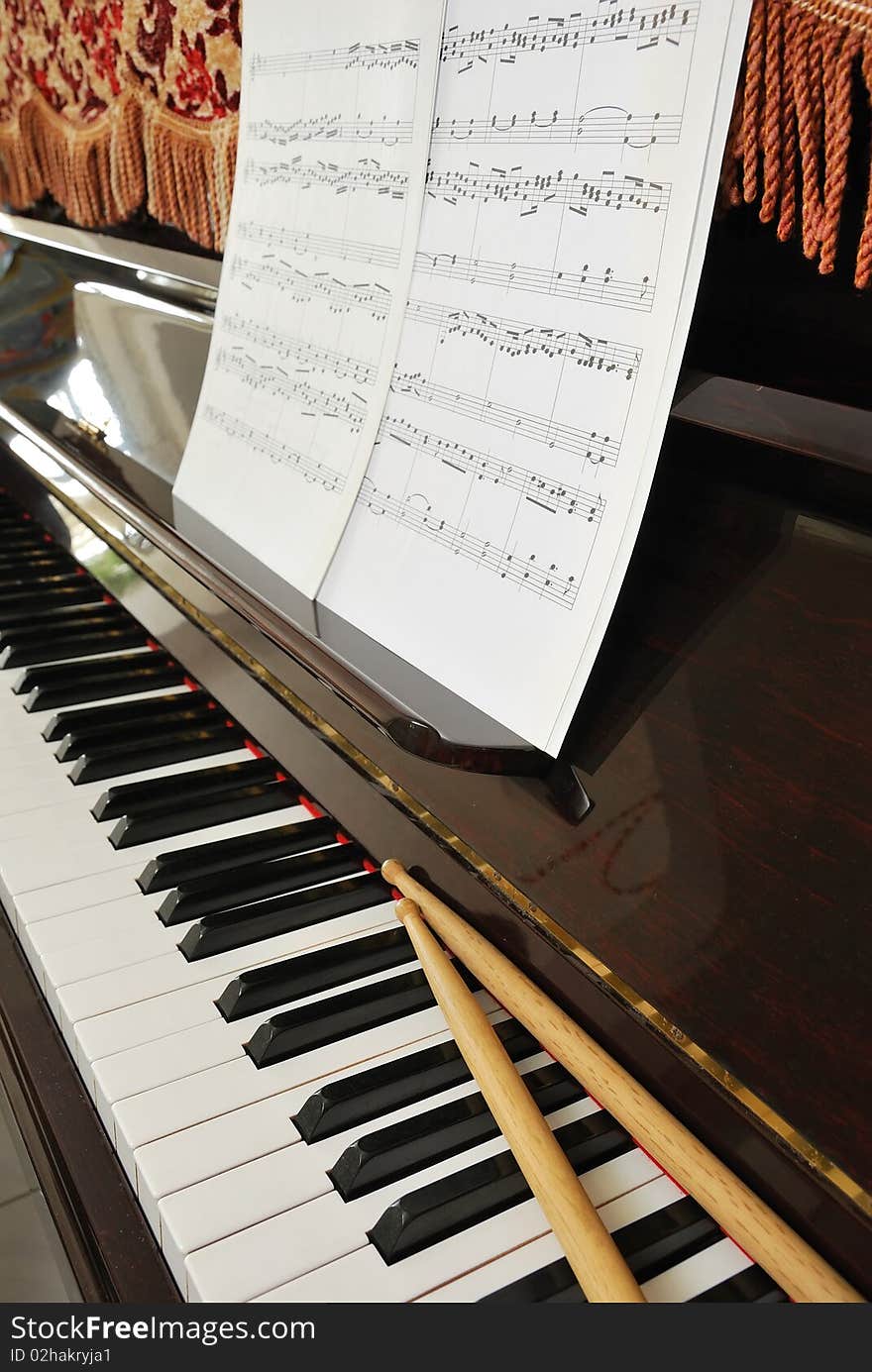 Music Score And Drum Sticks On Piano Keyboard