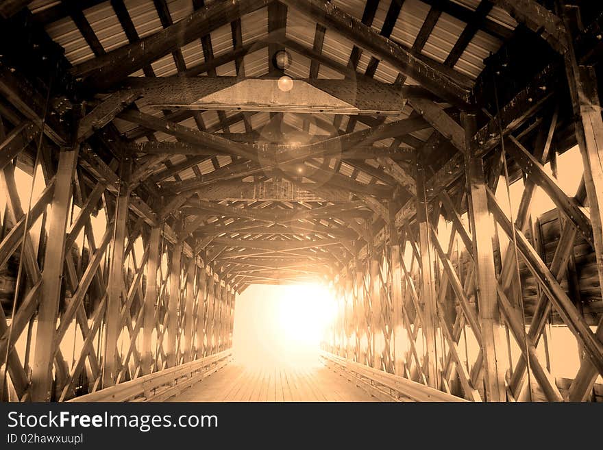 View of the interior wood structure of a covered bridge in sepia with lens flare. View of the interior wood structure of a covered bridge in sepia with lens flare