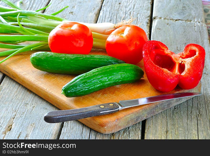 Vegetables for salad, tomatoes, peppers, cucumbers and onions on a cutting board. Vegetables for salad, tomatoes, peppers, cucumbers and onions on a cutting board