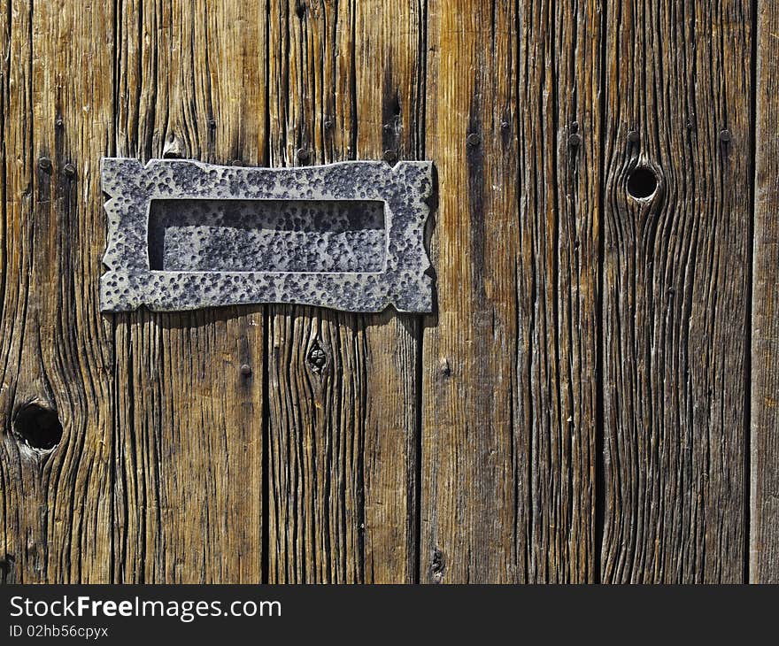 Metal mail slot mounted on rough wooden planked door. Metal mail slot mounted on rough wooden planked door