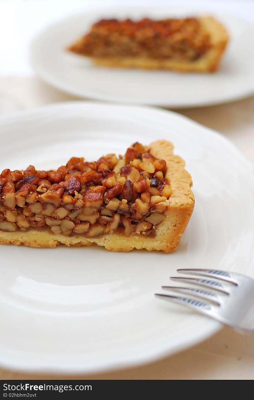 A single slice of hazel nut tart on white plate for dessert. For concepts such as food and beverage, diet and nutrition, and healthy eating. A single slice of hazel nut tart on white plate for dessert. For concepts such as food and beverage, diet and nutrition, and healthy eating.