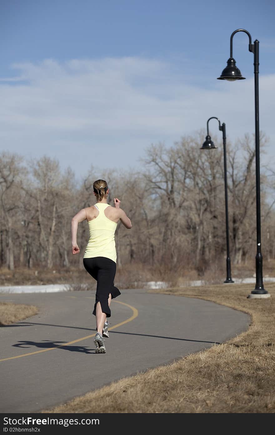 Young woman jogging on pathway. Young woman jogging on pathway.