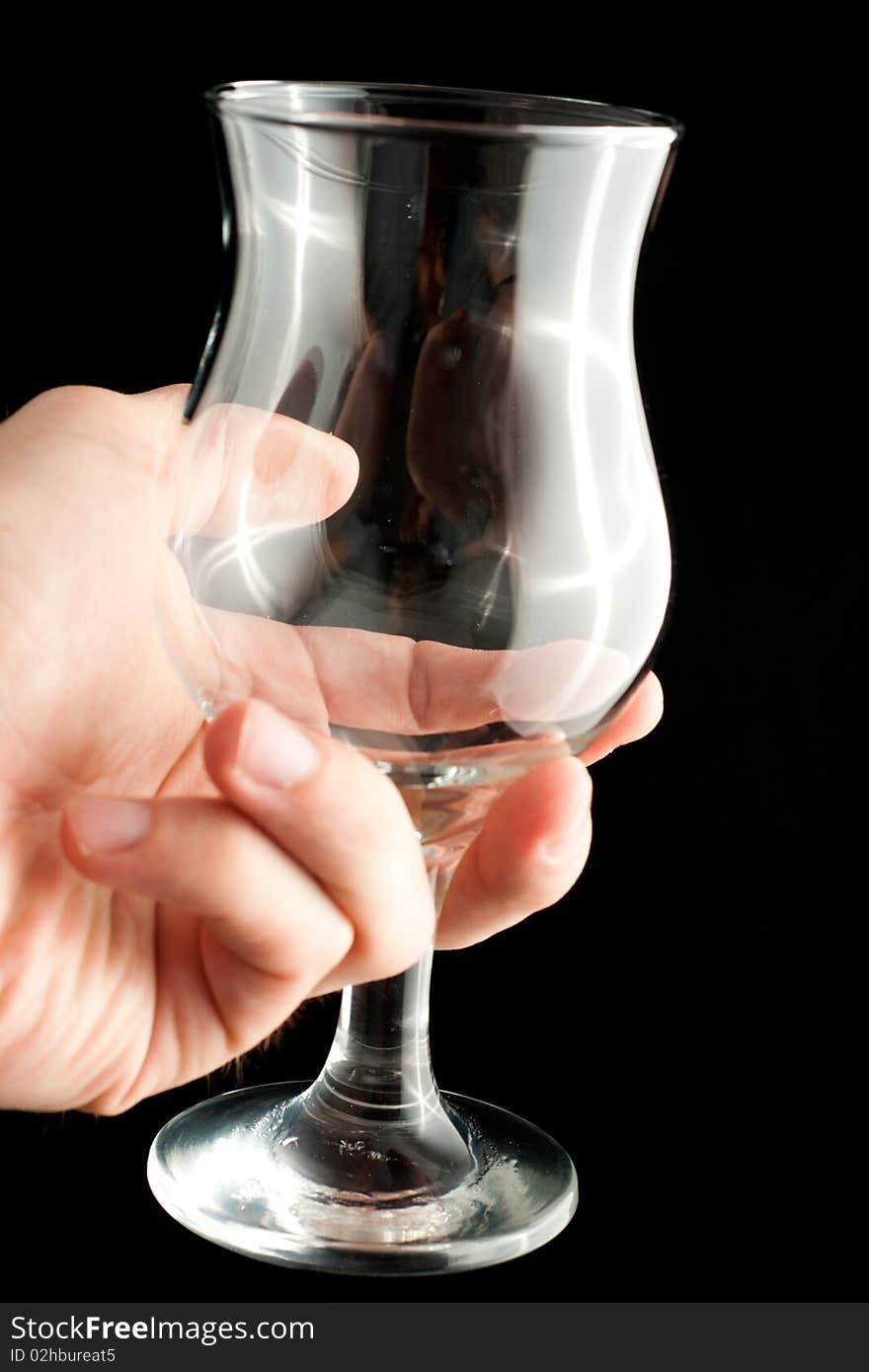 A wineglass in a hand isolated on black