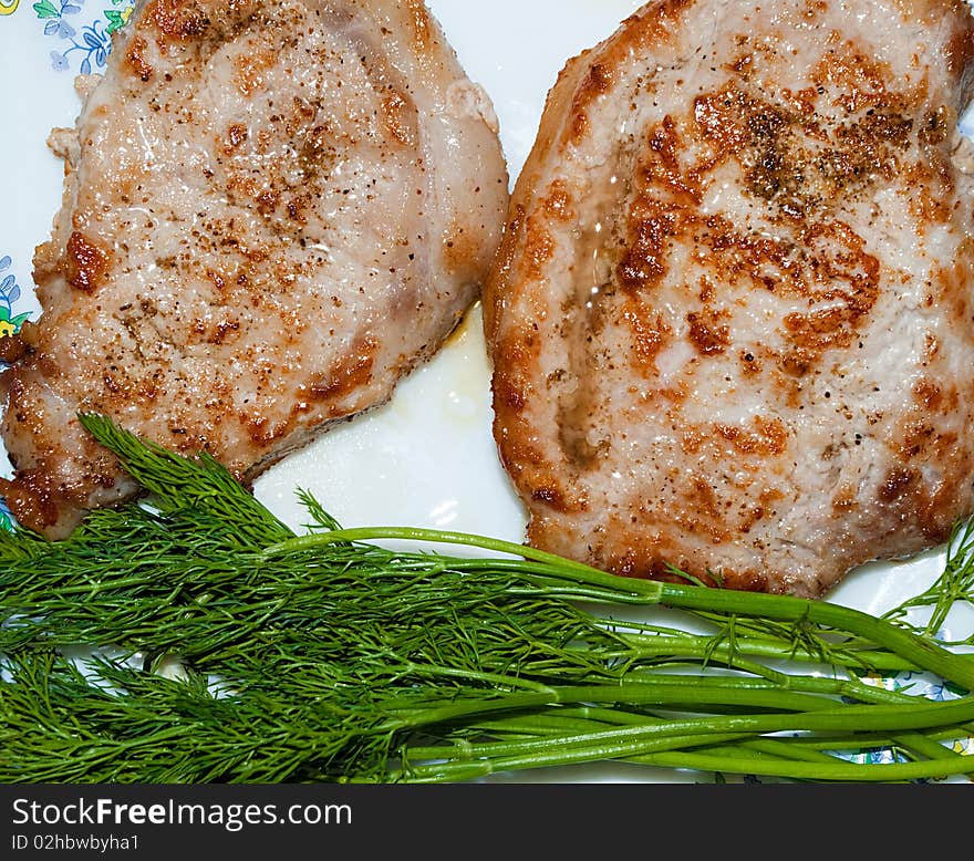 Pieces of juicy, fried meat with greens