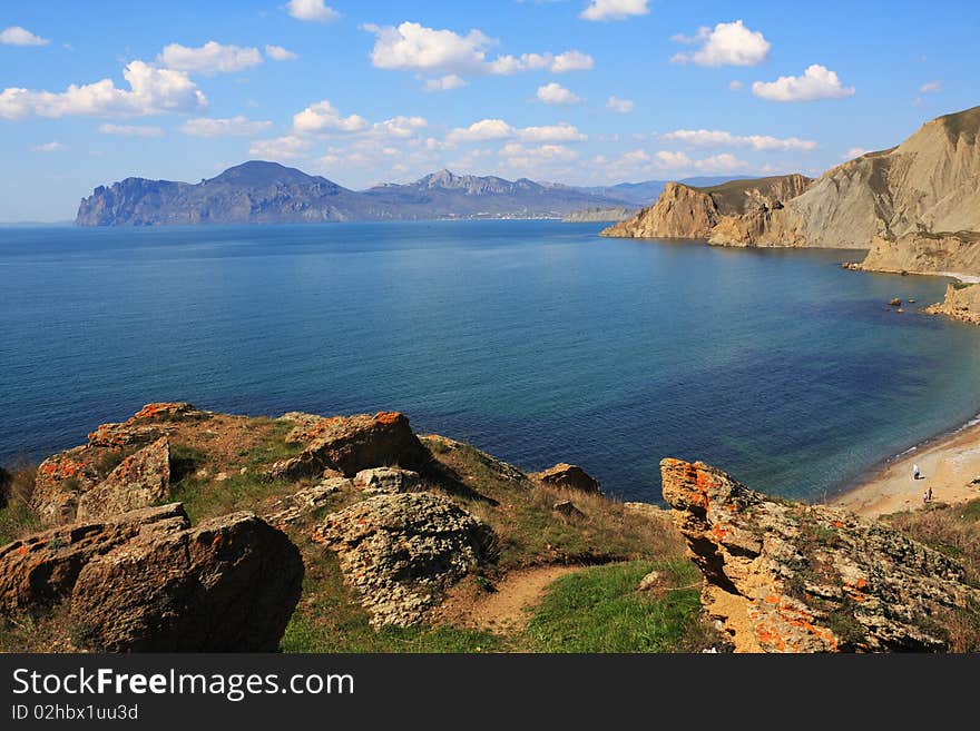 Seascape - a beautiful beach, sea and sky. In the foreground rocks and grass. Seascape - a beautiful beach, sea and sky. In the foreground rocks and grass