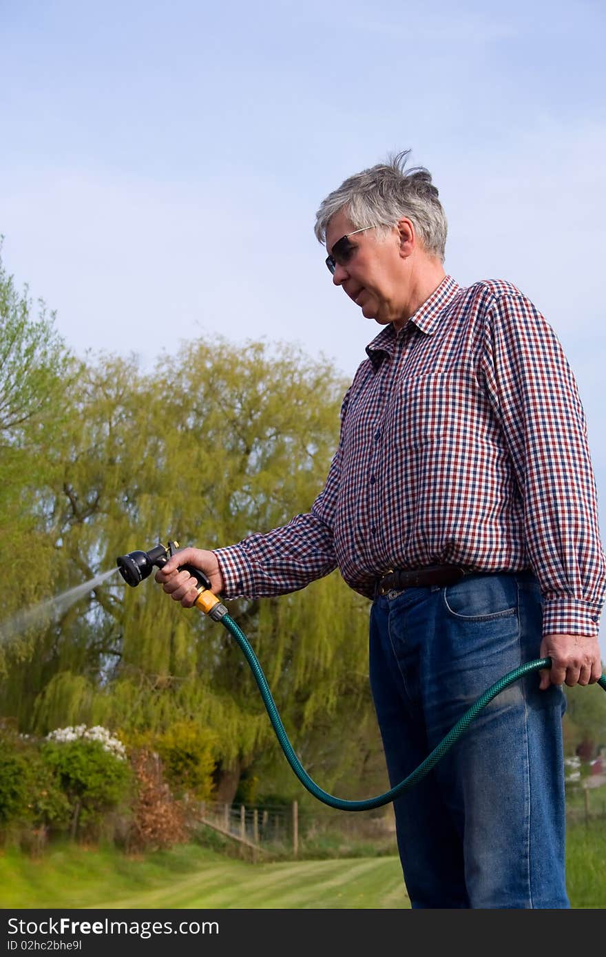 Mature Man Watering The Garden